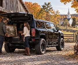 A couple loads a framed antique into a HUMMER EV in a New England town
