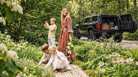 A family gathers outdoors beside a HUMMER EV